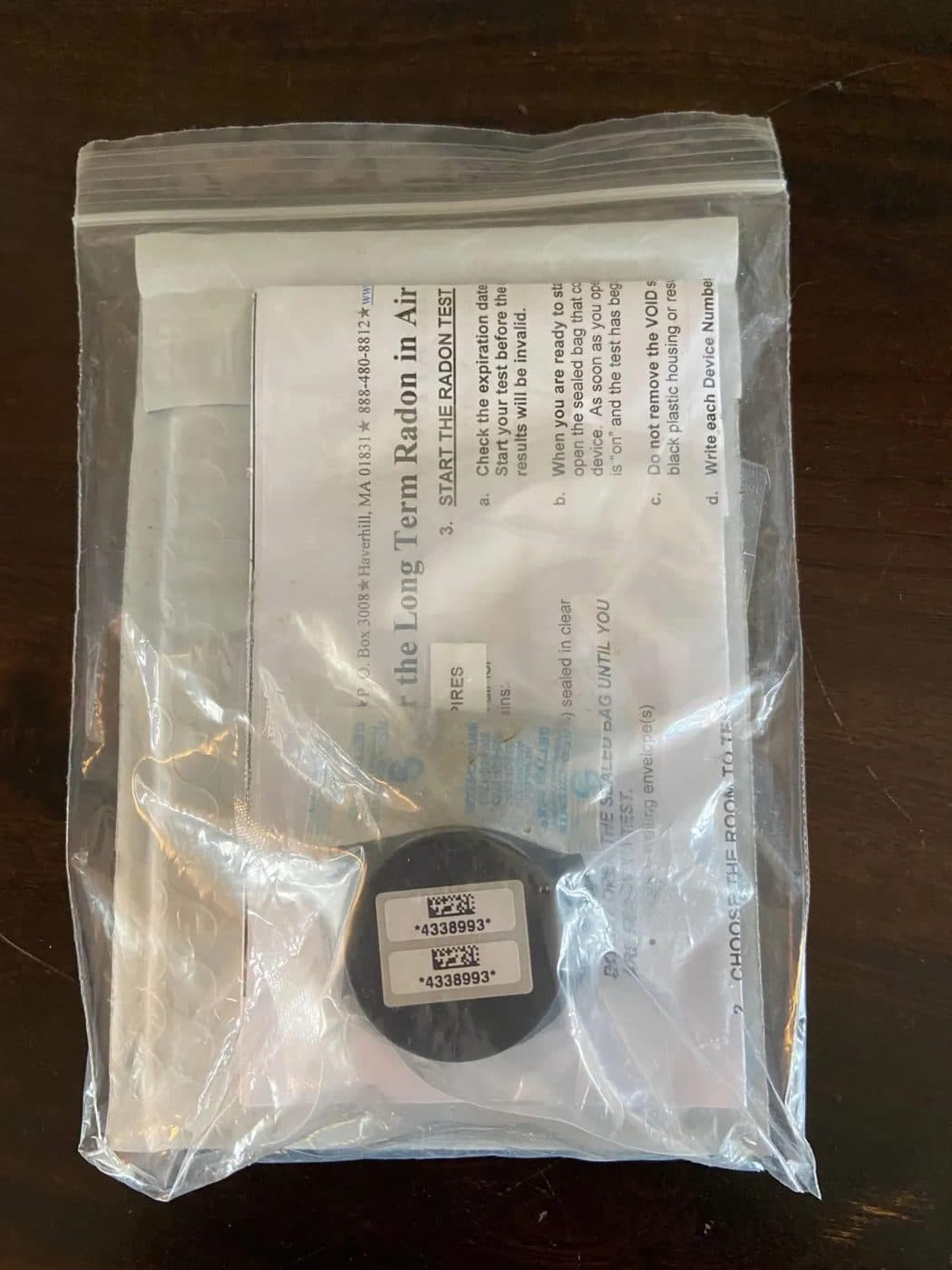 A sealed long-term radon test kit with its detector and instructions.